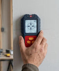 For Stud Finder Wall Scanner,5-in-1 Tester for stud Finder Metal Wire LCD in use against a wall with hand holding it.