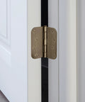 Built Thick Steel Interior Door Hinges Four Inch Antique Brass Finish Three Pack With Removable Pin For Smooth Daily Swinging And No Hassle Residential Installation close-up on an antique brass hinge installed on a white door.