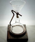 Deluxe Handcrafted Coffee Dripper For Hot Or Cold Brew With Adjustable Flow Valve And Smooth Maple Base creating coffee on dark wooden base.