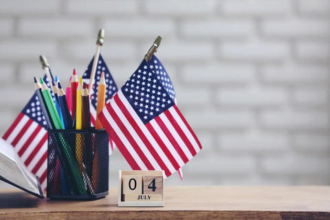 12 Pack Small American Flags 4x6 Inches Hand Held Stick Flags Spear Top Made In USA Patriotic Mini Flags on wooden desk with calendar