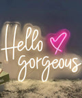 Decorative sign with "Hello Gorgeous" in white neon and pink heart accent, glowing softly on a fuzzy rug.