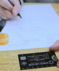 Mini Physics Multi Tool Ruler With Protractor And Compass Stainless Steel Gadget in use on a desk with notes and drawing compass