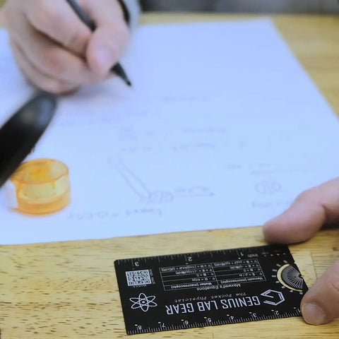 Mini Physics Multi Tool Ruler With Protractor And Compass Stainless Steel Gadget in use on a desk with notes and drawing compass