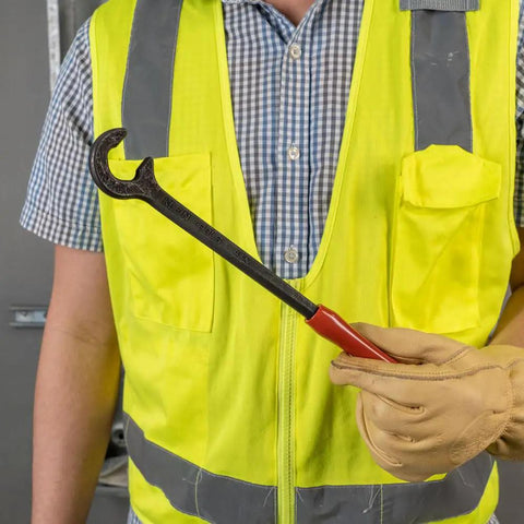 Worker holding a Heavy-Duty 12-Inch Cable Bender For 350 MCM Capacity Pro Grade Tool with Contoured Grip, one-piece forged steel.