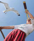 Child using Premium Brass Spyglass Telescope With Pocket Compass Set For Outdoor Adventures, bird overhead, leather grip visible.