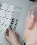 Person using Knockout Performance P Touch Pro Label Maker to organize electrical panel labels clearly.