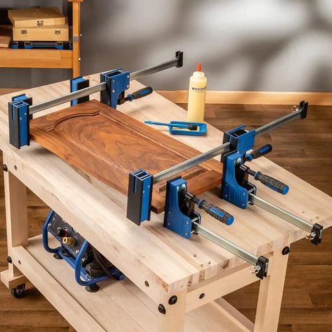 Beefy 24-Inch Parallel Bar Clamps For Woodworking on table, holding wooden panel, ergonomic handle, deep jaws, distributes 1000 lbs pressure