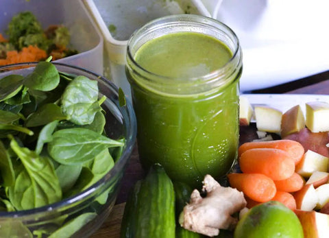 Fresh green juice with spinach, carrots, cucumber, and ginger next to Omega Juicer showing use of Auger Replacement Part PSCREW846