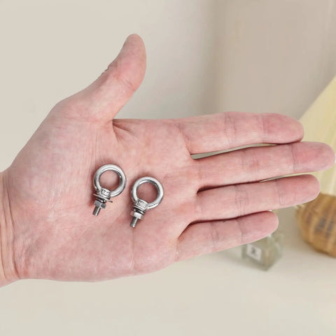 Premium Stainless Steel M4 Eye Bolts, Complete 24 Piece Hardware Set With Hex Nuts Flat And Spring Washers, shown in hand.
