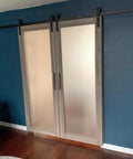 Kick Up Your Spaces With Top Shelf Double Sliding Barn Doors 42 X 96 Inches Featuring Ginger Ash Finish Frosted Glass Inserts Include Rugged Matte Black Rail Track And Complete Hardware Kit For Fast Bedroom Remodels, installed in a blue wall.