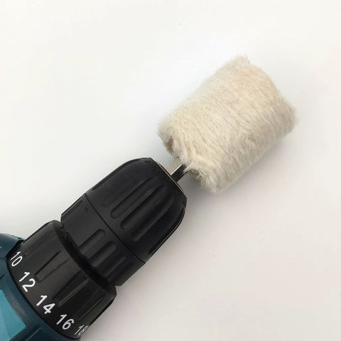 Buffing wheel for drill with white fluffy polishing pad mounted on a metal arbor, close-up