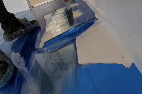 Worker using Metallic Colored Epoxies 18 Inch Epoxy Trowel Spreader Tool for smooth application on blue epoxy floor