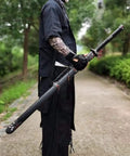 Person holding Hand Forged Longquan Style Dao Sword With High Carbon Steel Blade Full Tang And Dope Matte Black Wooden Scabbard