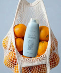 Quick Fix Leave In Hair Treatment Infuses Damaged Strands With Hella Hydration And Serious Shine For A Silky Smooth Finish in a mesh bag with oranges.