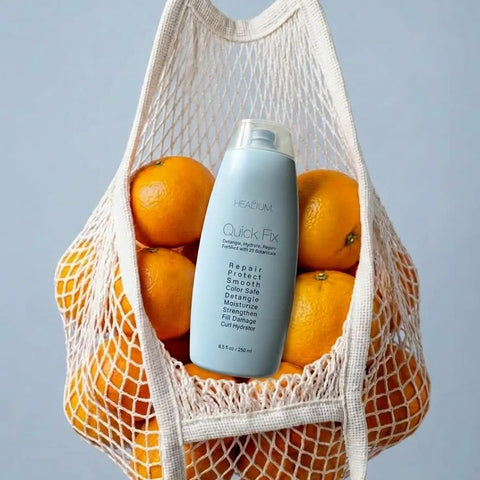 Quick Fix Leave In Hair Treatment Infuses Damaged Strands With Hella Hydration And Serious Shine For A Silky Smooth Finish in a mesh bag with oranges.