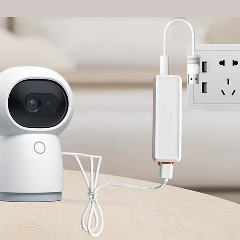 Mini UPS Battery Backup With 2600mAh Rechargeable Lithium Cell powers a security camera plugged into a wall outlet.