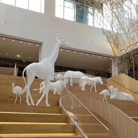 Sculptures of white animals on staircase in a modern interior space