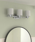 Chrome Vanity Bath Light Fixture With Etched Glass, Three Lights, 24 Inch Wide, mounted above a bathroom mirror