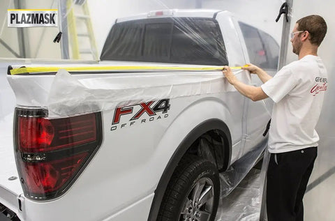 Man applying Pre Taped Masking Film With Three Quarters Inch Tape For Auto Body Protection to truck in paint booth