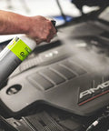 Person using All In One Car And Workshop Universal Cleaner Highly Concentrated And Dilutable on car engine in a workshop setting.