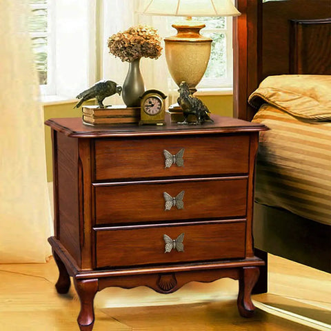 Pack Of 5 Vintage Butterfly Cabinet Door Knobs In Antique Bronze Finish On Wooden Nightstand In Bedroom Setting