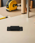 Hidden Door Hinge 5 Inch Black Concealed Pivot for cabinets and secret doors positioned on a beige table with tools
