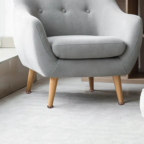 Felt Chair Leg Pads And Caster Cups Set For Hardwood Floors protecting wooden legs of a gray armchair, light brown color.