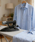 Heavy Duty Commercial Steam Iron Featuring Badass High Pressure Performance For Smooth Garment Pressing Factory Dry Cleaning And Bulletproof Temperature Control on ironing board with blue shirts.