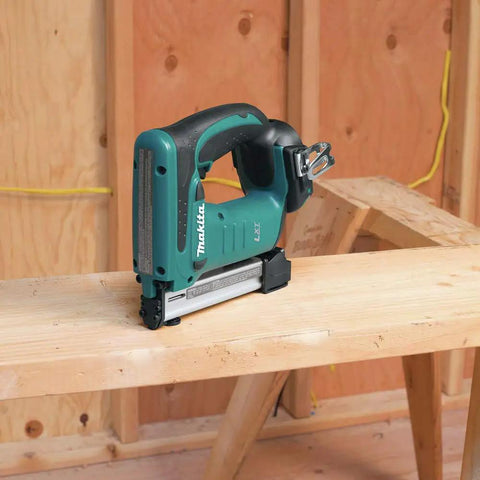 18V LXT Crown Stapler With Easy Depth Control Knob placed on wooden surface in workshop setting, showing see-through magazine window