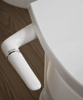 No Fuss Easy Install Bidet Toilet Seat M250 with manual adjustable spray handle on white elongated seat, wood floor background.
