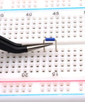 Tweezers placing component on a breadboard from the 560 Piece Breadboard Jumper Wire Kit With PCB Circuit Board Assortment.