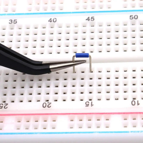 Tweezers placing component on a breadboard from the 560 Piece Breadboard Jumper Wire Kit With PCB Circuit Board Assortment.