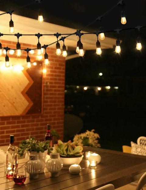 Outdoor LED String Lights 50Ft With 16 Shatterproof S14 Bulbs illuminating a patio dining area with warm white light.