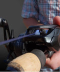 Vertix LP Baitcasting Reel Pro Grade Performance With 7 Plus 1 Ball Bearings, 20 Lb Carbon Fiber Drag in hand, dark gray.