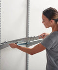 Woman installing Seven Pair Pants Rack For Closets In Titanium Finish With Non Slip Grippers And Slick Ball Bearing Glide