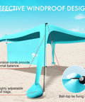 Close-up of blue 10x10 beach shade canopy tent with sidewalls showing windproof design setup on sand with guylines.