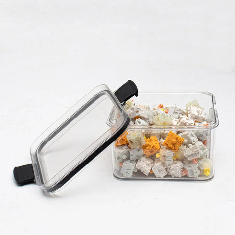 Side view of a transparent plastic keyboard switch storage box (460 ml) with clear lid and mixed switches