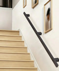 Rock Solid Black Wrought Iron Handrail For Stairs And Hallways With Hidden Mounting Screws Plus Durable Non Slip Grip and Decorative Support Railing mounted on a wall beside wooden stairs.