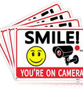 Legit Heavy Duty Aluminum Security Camera Signs Straight Up Warning To Scare Off Thieves Keep Your Home Yard Or Business Locked Down Bright Orange Black Cctv 4 Pack in a stack showing smiley face and camera graphics.