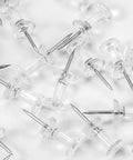 Legit Durable Push Pins 600 Count Standard Thumb Tacks With Kickass Steel Points And Clear Rounded Tops scattered on a surface.