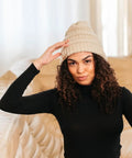 Woman wearing a cream-colored Satin Lined Beanie For Curly Hair Women Cozy Cable Knit Winter Hat With Frizz Free Moisture Retaining Satin Interior