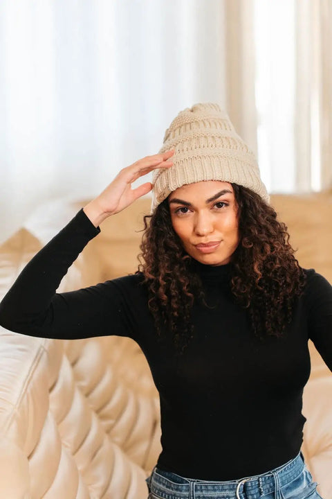 Woman wearing a cream-colored Satin Lined Beanie For Curly Hair Women Cozy Cable Knit Winter Hat With Frizz Free Moisture Retaining Satin Interior