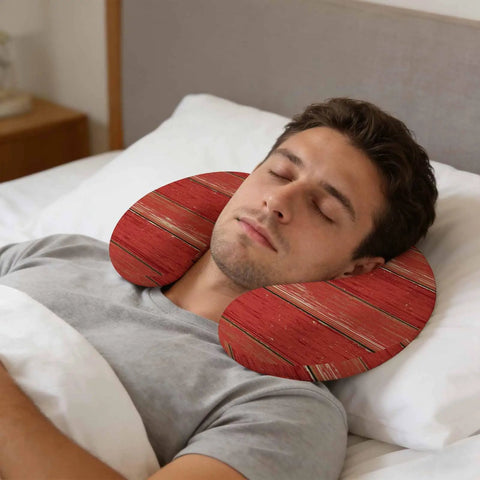 Man sleeping with U Shape Memory Foam Travel Pillow With Red Wood Grain Finish For Airplane Rides Car Trips Office Or Home Ergonomic Neck Support Portable Comfy Rest For A Restful Sleep Anywhere in bed.