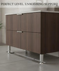 Rock Solid Adjustable Height Aluminum Cabinet Leg With Oxidized Finish supports a wooden vanity on an uneven floor.