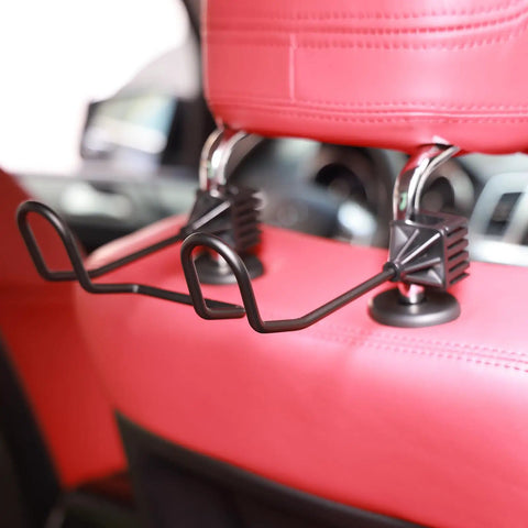Dual Hook Hard Hat Holder For Truck Seats And Car Back Seats installed on headrest, showing black metal hooks on red seat.