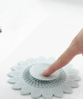 Floor Drain Plug Shower Bathtubs Drain Covers, Flower, White on a sink with a finger pressing down for hair catching.