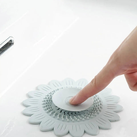 Floor Drain Plug Shower Bathtubs Drain Covers, Flower, White on a sink with a finger pressing down for hair catching.