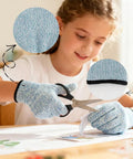 Child wearing 4 Pcs Cut Resistant Kids Gloves Ages 8 To 12 Level 5 Protection Food Grade Kid Safe For Cooking Kitchen Dishwashing Gardening And Woodworking Blue Durable And Flexible For Easy Handling In The Kitchen Or Workshop For Cooking Crafts And Diy Projects, cutting paper with scissors.