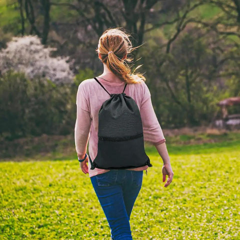 Person walking outdoors with a Durable Black Drawstring Backpack For Gym And Everyday Carry No Fuss Use With Thick Polyester Material