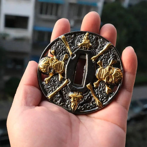 Dope Alloy Tsuba Fuchi Kashira Menuki Set For Samurai Sword Handle Upgrade 8 To 9 Cm Tsuba in hand, skull design in gold and black.